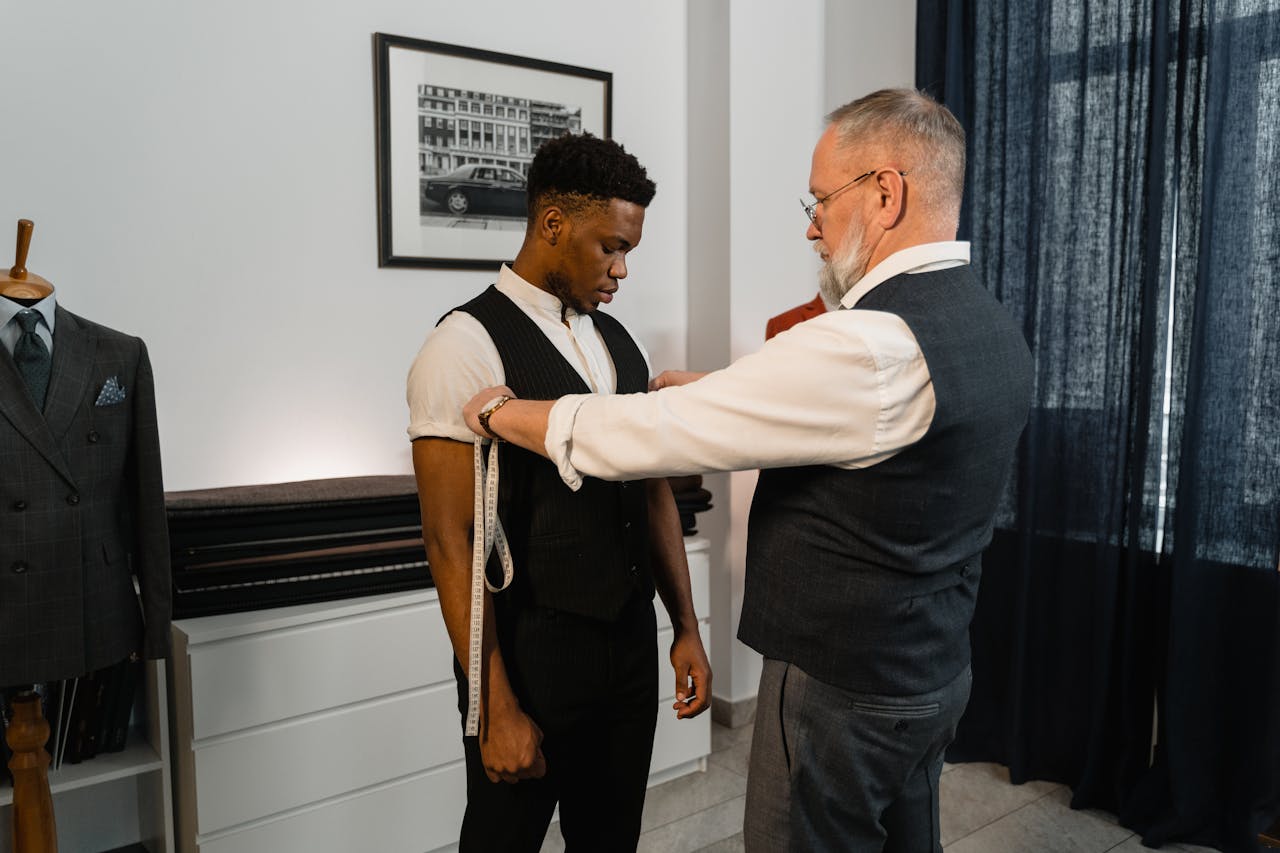 home-img Tailor taking measurements of a client for a bespoke suit in a stylish atelier.