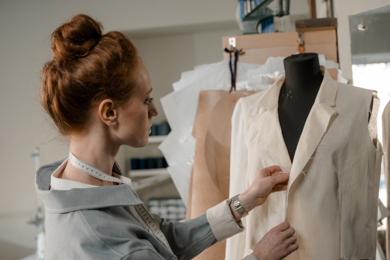 gallery-03 A woman tailor carefully working on a dress on a mannequin in her studio.