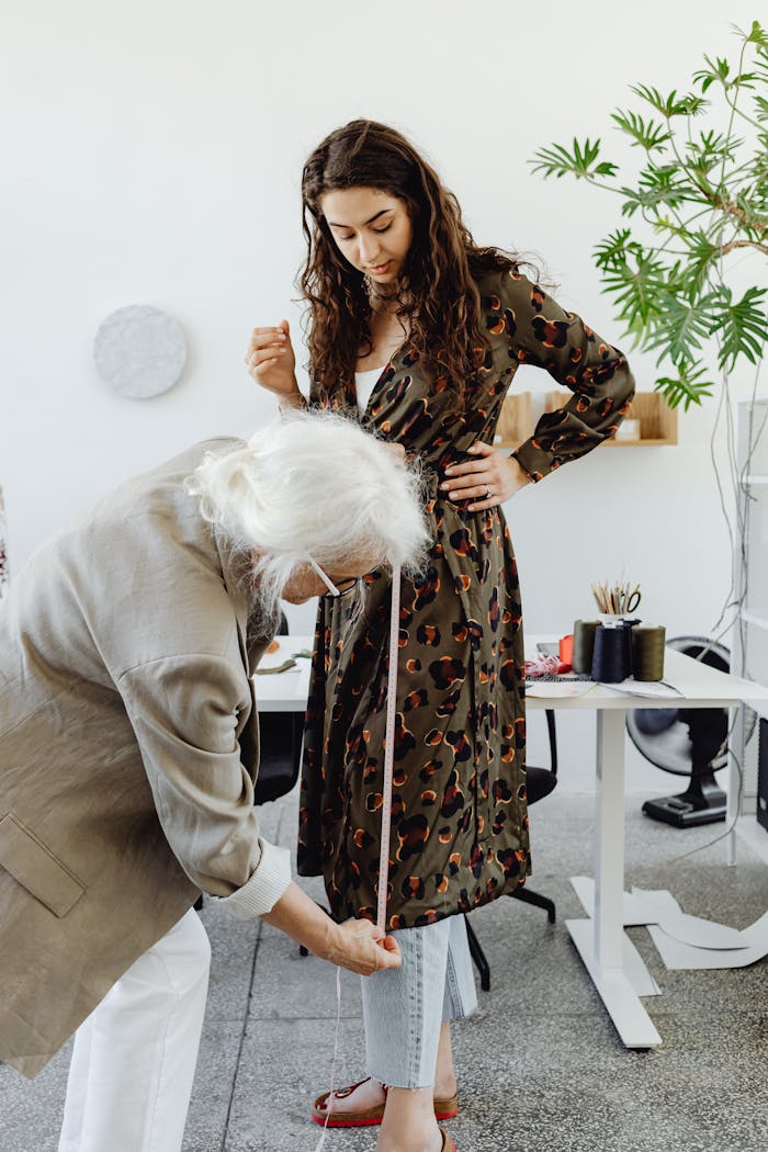 gallery-02 A tailor using a measuring tape with a young woman in a fashion design studio.
